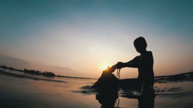 Küçük çocuk yapılar bir kum kale günbatımında siluet