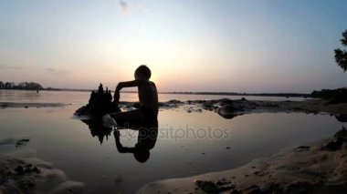 Küçük çocuk yapılar bir kum kale günbatımında siluet