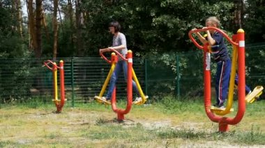Ağır çekimde spor için anne ve oğlu Street egzersiz makineleri içeri