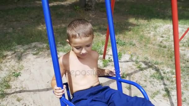 Niño feliz balanceándose en un columpio en cámara lenta — Vídeos de Stock