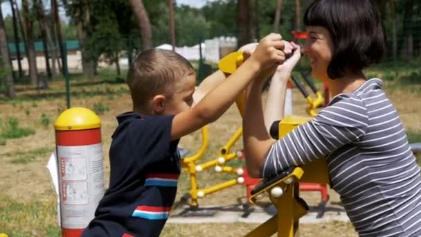 Mère et enfant sur les machines d'exercice de rue vont dans le sport au ralenti — Video