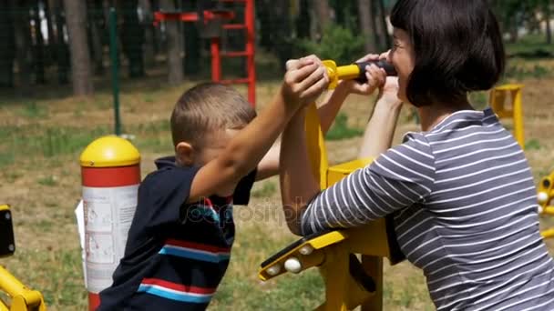 La madre y el niño en las máquinas de ejercicio callejeras hacen deporte en cámara lenta — Vídeos de Stock