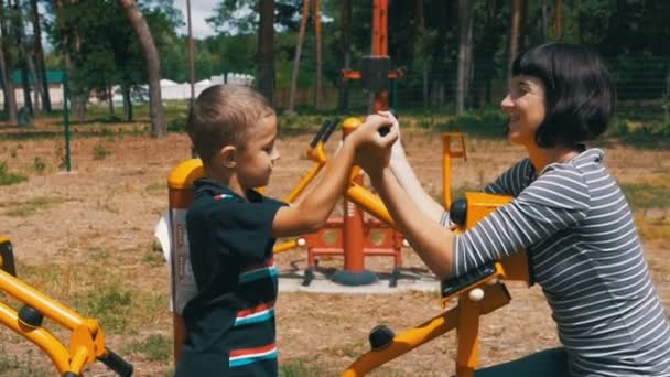La madre y el niño en las máquinas de ejercicio callejeras hacen deporte en cámara lenta — Vídeos de Stock