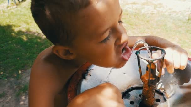 Happy Little Boy divertente acqua potabile da una fontana per bere sul campo da gioco in slow motion — Video Stock