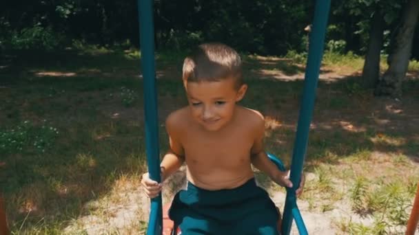 Niño feliz balanceándose en un columpio en cámara lenta — Vídeo de stock