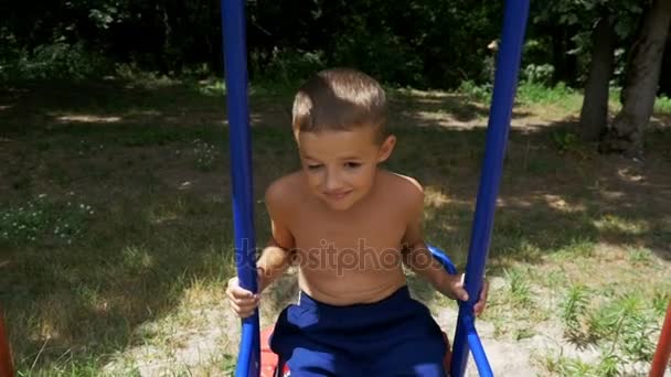 Heureux petit enfant garçon balançant sur un balançoire dans ralenti mouvement — Video