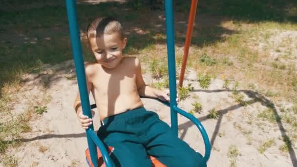 Χαρούμενος μικρό παιδί αγόρι κουνιέστε σε μία κούνια σε αργή κίνηση — Αρχείο Βίντεο