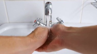 Musluktan akan suyun altında lavaboda el yıkama adam