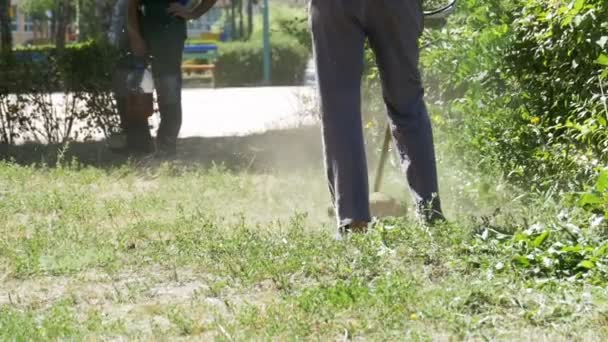 Человек косит траву с помощью портативной газонокосилки в медленном движении — стоковое видео