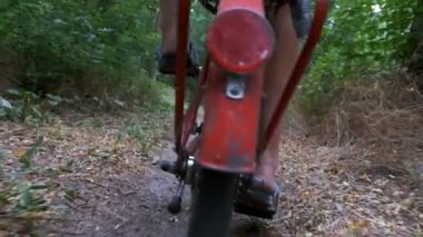 Perçin çivileri ormandaki bir yolda sürme bir bisiklet üzerinde bir adamın bacaklar. Ağır çekim