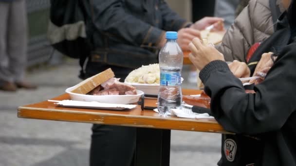 Die Leute im Straßencafé stehen an einem Tisch und essen Fast Food. Prag, Tschechische Republik — Stockvideo