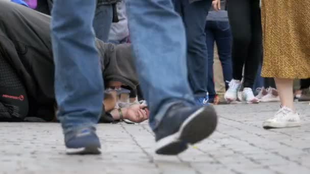 Бездомный нищий в шляпе на тротуаре просит милостыню у проходящих мимо людей — стоковое видео
