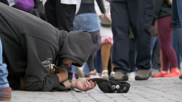 Hemlösa tiggare Man med en hatt på trottoaren ber om allmosor från förbipasserande — Stockvideo