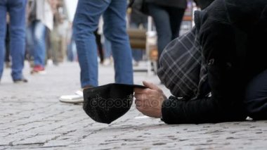 Sadaka üzerinden geçen insanlar için kaldırımda şapkalı evsiz dilenci adam yalvarır