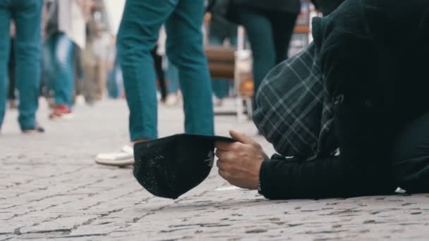 Άστεγοι ζητιάνος άνθρωπος με ένα καπέλο στο πεζοδρόμιο ικετεύει για ελεημοσύνη από τους ανθρώπους που περνούν από — Αρχείο Βίντεο
