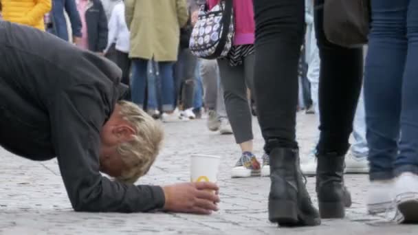 Obdachloser Bettler mit Plastikbecher in der Hand bettelt auf dem Bürgersteig um Almosen von Passanten — Stockvideo