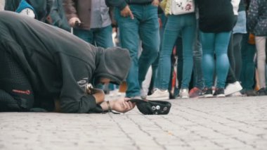 Kaldırımda şapkalı evsiz dilenci adam sadaka üzerinden geçen insanlar için yalvarır. Ağır çekim