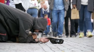 Kaldırımda şapkalı evsiz dilenci adam sadaka üzerinden geçen insanlar için yalvarır. Ağır çekim