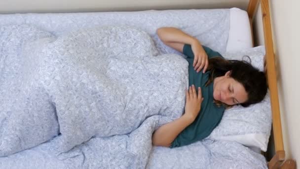 Vue du dessus de la fille se réveille et s'étend couché sur le lit avec une couverture blanche le matin — Video