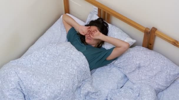 Top view of Sleepy Girl wakes up and stretches lying down with a white blanket in the morning — Stock Video