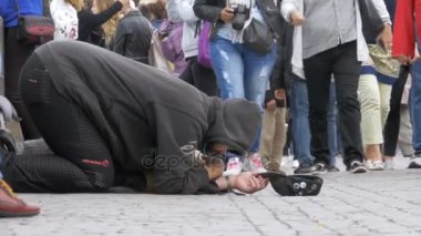 Sadaka üzerinden geçen insanlar için kaldırımda şapkalı evsiz dilenci adam yalvarır