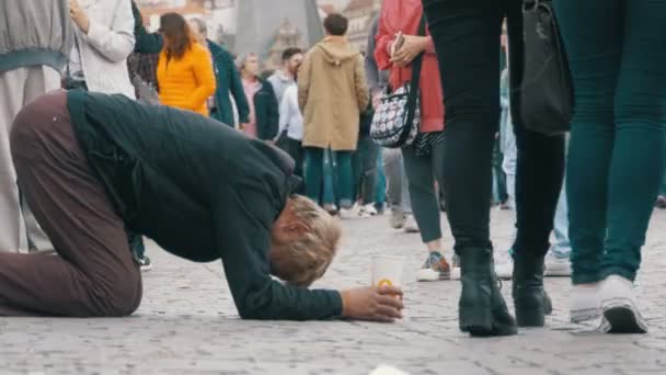 Obdachloser Bettler mit Plastikbecher in der Hand bettelt auf dem Bürgersteig um Almosen von Passanten — Stockvideo