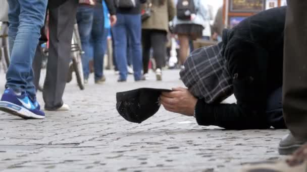 Hemlösa tiggare Man med en hatt på trottoaren ber om allmosor från förbipasserande — Stockvideo