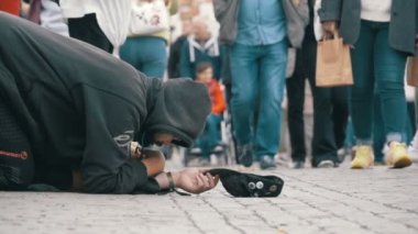 Kaldırımda şapkalı evsiz dilenci adam sadaka üzerinden geçen insanlar için yalvarır. Ağır çekim