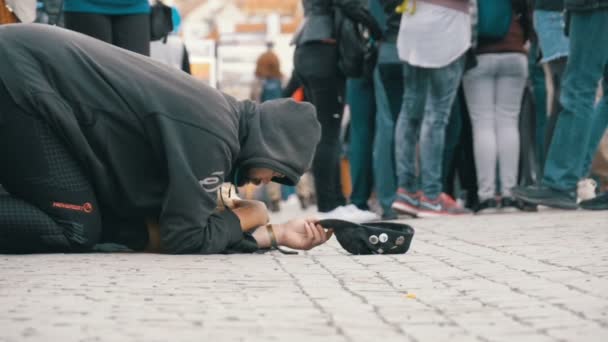 Obdachloser Bettler mit Hut auf dem Bürgersteig bettelt um Almosen von Passanten. Zeitlupe