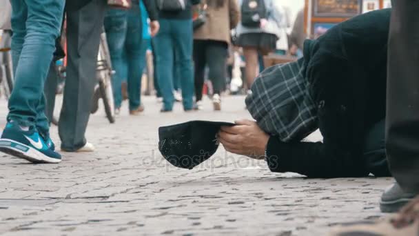 Beggar hajléktalan ember egy kalapot a járdán könyörög az alamizsnát, a járókelők — Stock videók