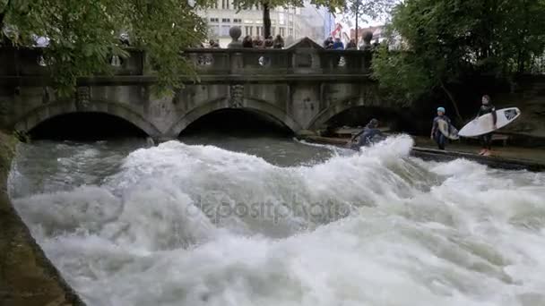 Münih, Almanya'nın ortasındaki Eisbach nehrinde insan yapımı bir dalga üzerinde kentsel sörfçü — Stok video