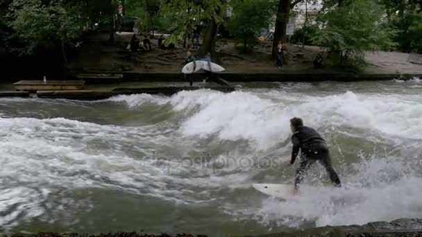 Городские серфингисты катаются на постоянной волне по реке Айсбах, Мюнхен, Германия. Slow Motion — стоковое видео