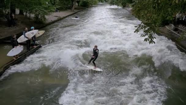 Městská surfaři jezdit stojatá vlna na řece Eisbach, Mnichov, Německo. Zpomalený pohyb — Stock video