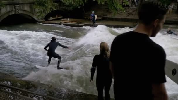 Urbana surfare på en konstgjorda våg på Eisbach river i centrala München. Slow Motion — Stockvideo