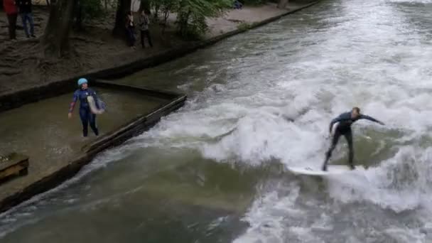 Городские серферы на рукотворной волне на реке Эйсбах в центре Мюнхена, Германия — стоковое видео