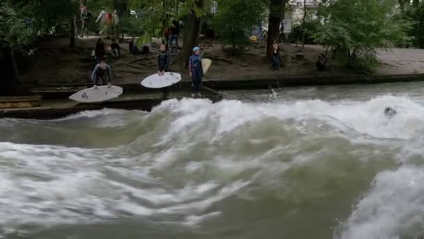 Городские серферы катаются на стоячей волне по реке Эйсбах, Мюнхен, Германия — стоковое видео