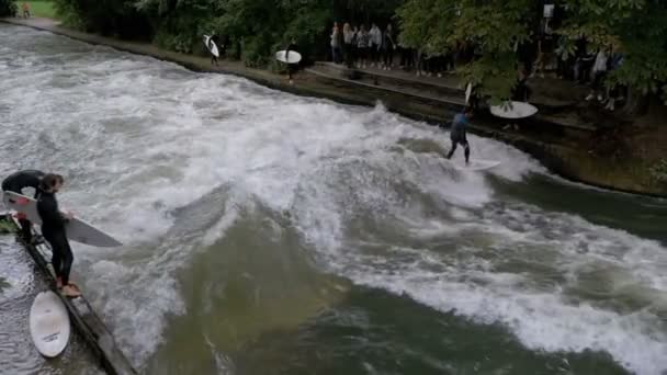 Urban Surfers en una ola artificial en el río Eisbach en el centro de Munich. Moción lenta — Vídeo de stock