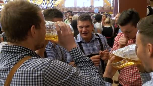 Opilý Pánská uvnitř velké pivní hospoda s džbánky na pivo v jejich rukou oslavit Oktoberfest. Bavorsko, Německo. — Stock video