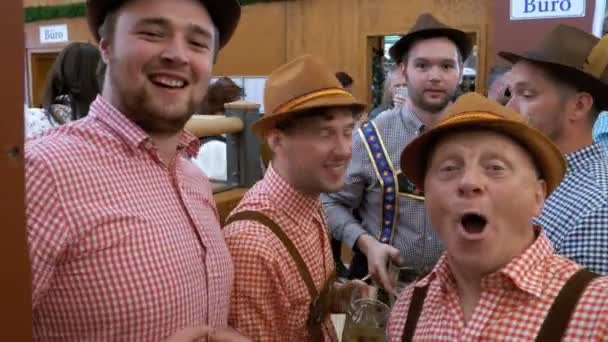 Hombres borrachos dentro de un gran pub de cerveza con tazas de cerveza en sus manos celebran el Oktoberfest. Baviera, Alemania . — Vídeos de Stock