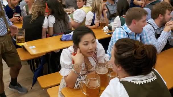 Pijanych ludzi przy stole świętować Oktoberfest wewnątrz namiotu dużego piwa. Bawaria, Niemcy — Wideo stockowe