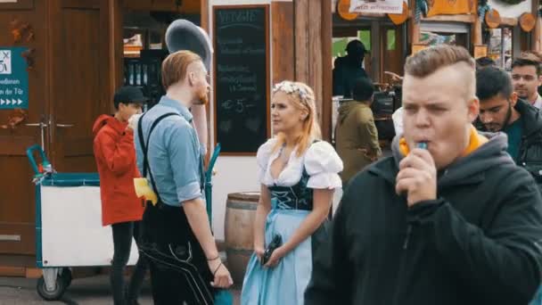 Menschen in bayrischen Trachten laufen über die Straße des Oktoberfests. Bayern, Deutschland