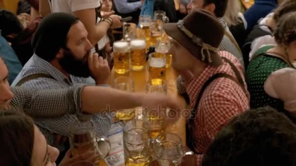 La gente borracha en la mesa celebra el Oktoberfest dentro de una gran tienda de cerveza. Baviera, Alemania — Vídeos de Stock
