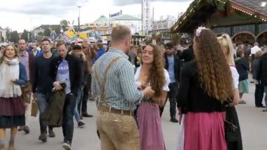 İnsanlar ulusal Bavyera giysili Oktoberfest festival alanı cadde boyunca yürüyüş. Münih, Almanya