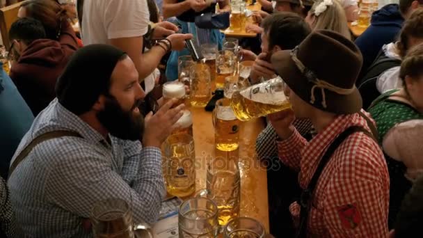 La gente borracha en la mesa celebra el Oktoberfest dentro de una gran tienda de cerveza. Baviera, Alemania — Vídeo de stock