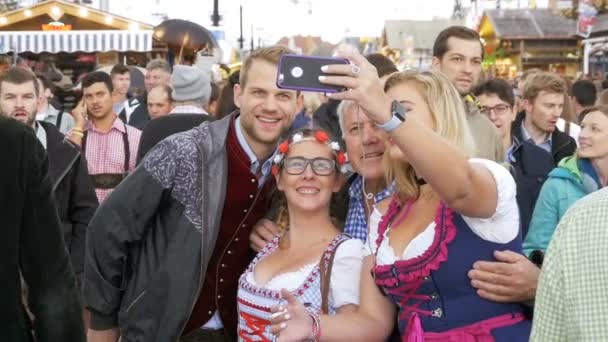 La gente hace foto selfie en trajes nacionales bávaros en la calle de Oktoberfest. Baviera, cámara lenta — Vídeos de Stock