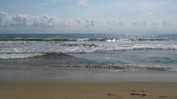 A tenger hullámai gurul a homokos strandon, lassítva