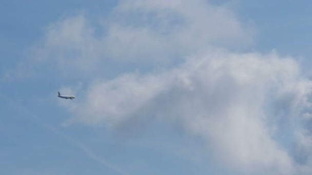 El avión de pasajeros vuela lejos en el cielo azul por encima de las nubes — Vídeos de Stock