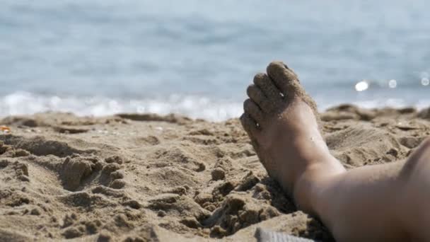 Lábak a nő feküdt, strandon, a tenger közelében — Stock videók