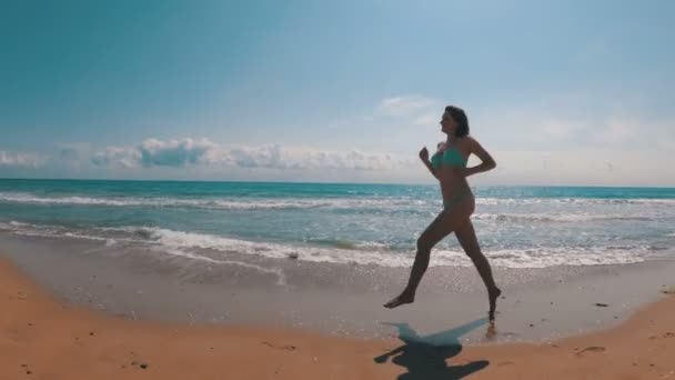 A câmera está se movendo atrás da mulher correndo ao longo do mar Praia em câmera lenta — Vídeo de Stock