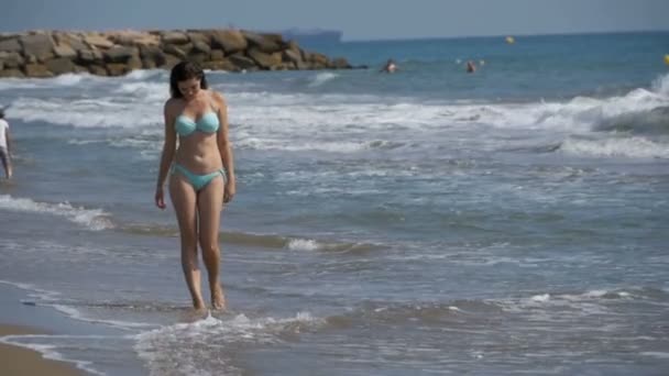 Дівчина в купальнику проходить вздовж берега моря, біля пляжу в уповільненому Русі — стокове відео
